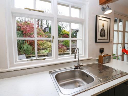 a kitchen with a sink and two windows at Croft Cottage in Long Marton