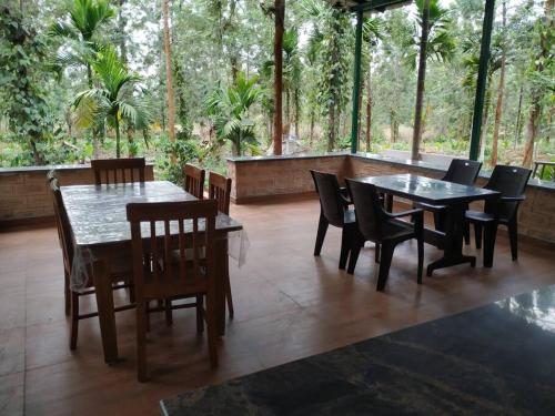 uma sala de jantar com mesas, cadeiras e árvores em VANIKA PLANTATION em Kikkeri