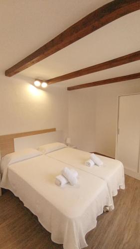 a bedroom with two beds with white sheets and towels at CASA DEL ARBOL DE BIBIANA 2 in Hermigua
