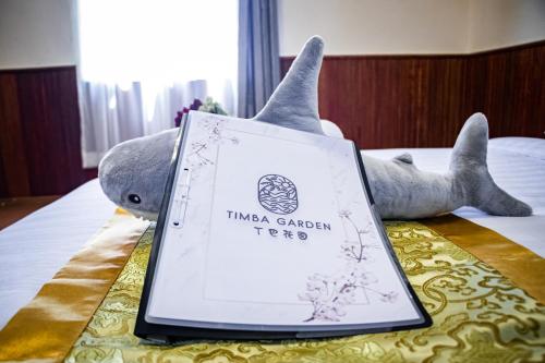 a stuffed elephant is laying on a bed with a book at Timba Garden FREE TOWN AND JETTY TRANSPORT in Semporna