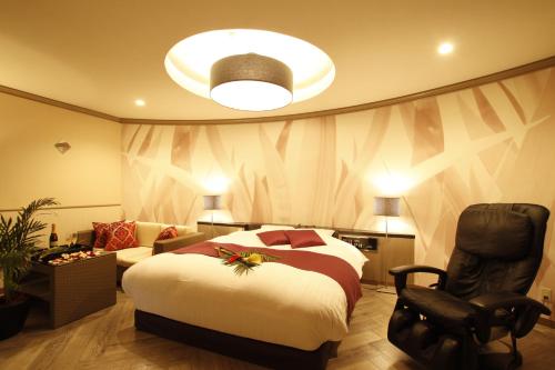 a hotel room with a bed and a chair at HOTEL MUSEE Rifu -Adult Only- in Rifu