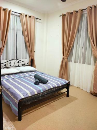 a bedroom with a bed with a blue comforter and curtains at Al Hidayah Suite in Bandar Seri Begawan