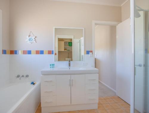 a white bathroom with a sink and a shower at Hastings Cove Holiday Apartments in Hastings Point