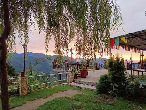 d'une terrasse avec un arbre et une vue sur les montagnes. dans l'établissement Madhuvan Cottages Homestay Mukteshwar, à Mukteswar