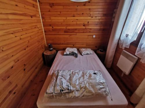 Bett in einem Zimmer mit einer Holzwand in der Unterkunft Le refuge in Saint-Pierre-dels-Forcats