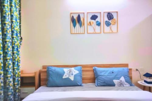 1 dormitorio con 1 cama con almohadas azules y cuadros en la pared en Quiet & Cozy Resort Style Fully Furnished 1-BHK Apartment, en Dabolim