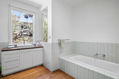 a white bathroom with a tub and a window at Sea Corner in Anglesea