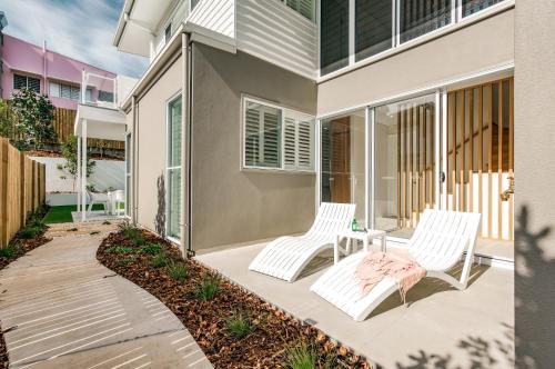two white chairs on a patio in front of a house at Essence Peregian Beach Resort - Saltbush 5 Bedroom Luxury Home with Private Pool in Peregian Beach