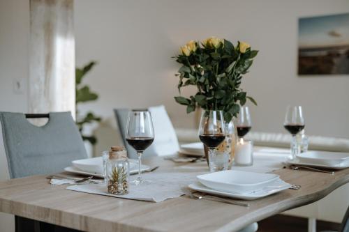 einen Holztisch mit Gläsern Wein und eine Vase Blumen in der Unterkunft Stilvolles Appartement mit Blick auf das Dreiflüsse-Eck in Passau