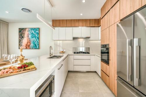 a kitchen with white countertops and wooden cabinets at Essence Peregian Beach Resort - Saltbush 5 Bedroom Luxury Home with Private Pool in Peregian Beach