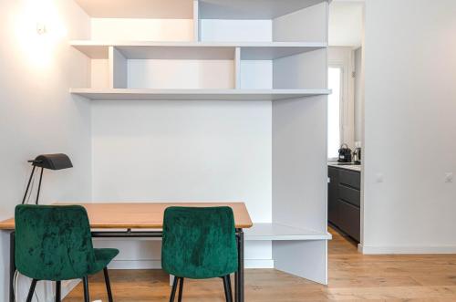 une salle à manger avec une table et deux chaises vertes dans l'établissement Appartement Architecte Catalans- Bord de mer, à Marseille