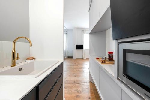 eine weiße Küche mit einer Spüle und einer Mikrowelle in der Unterkunft Appartement Architecte Catalans- Bord de mer in Marseille