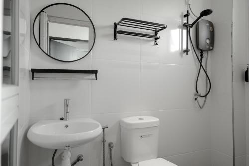 uma casa de banho branca com um lavatório e um espelho em Langkawi Homestay at Simfoni Beliza Apartment by Chien em Kuah