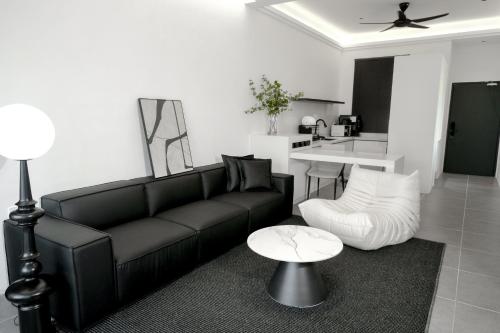 a living room with a black couch and a table at Langkawi Homestay at Simfoni Beliza Apartment by Chien in Kuah