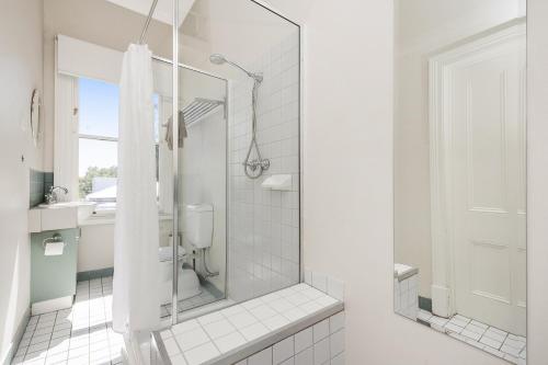 a white bathroom with a shower and a toilet at Apartment Faro in Fremantle