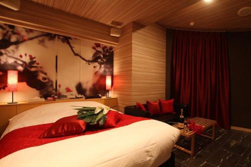 a bedroom with a large bed with red pillows at ホテルミュゼ愛子Hotel MUSEE Ayashi in Sendai