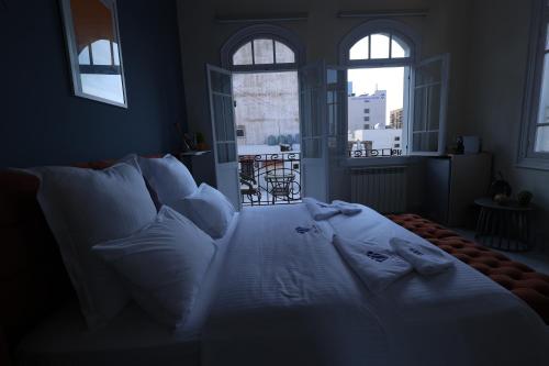 a bedroom with a bed with white sheets and pillows at THE GEM BOUTIQUE HOTEL in Beirut