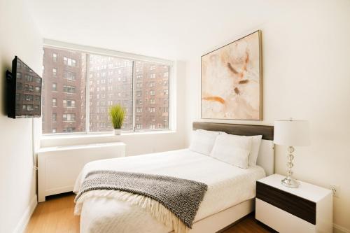 a white bedroom with a bed and a window at Lovely 2 Bedroom Apartment in New York