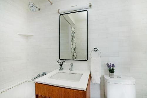 a white bathroom with a sink and a mirror at Lovely 2 Bedroom Apartment in New York