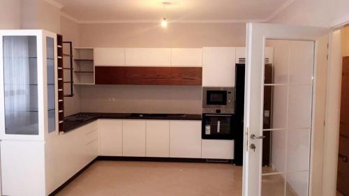 a kitchen with white cabinets and a microwave at Private Apartament in Peshkopi, Albania in Peshkopi