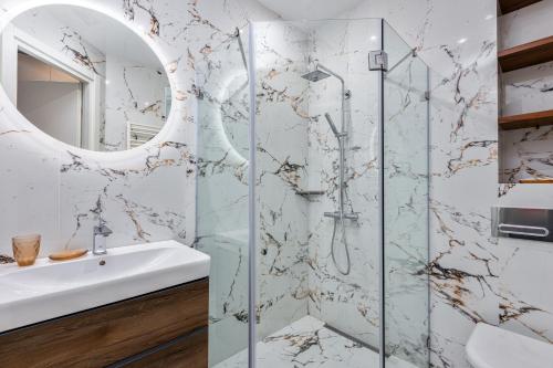ein Bad mit einer Dusche, einem Waschbecken und einem Spiegel in der Unterkunft HCG Art'Muse Apartment in Batumi