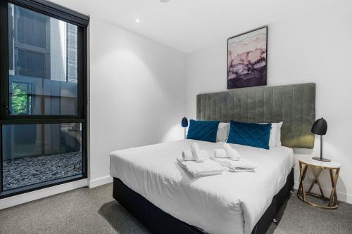 a bedroom with a large bed and a window at The Eminence Apartments by CLLIX in Melbourne