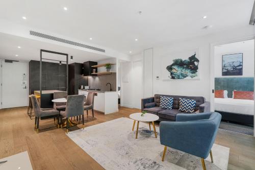 The Eminence Apartments by CLLIX في ملبورن: غرفة معيشة مع أريكة وطاولة