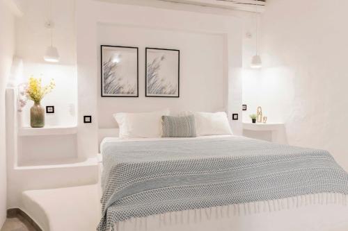 a white bedroom with a bed and two pictures on the wall at Kouros Exclusive Hotel & Suites - Adults Only in Faliraki