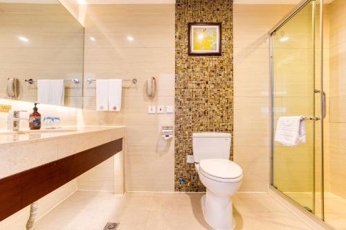 a bathroom with a toilet and a glass shower at Metropark Changchun Guosheng Hotel in Changchun