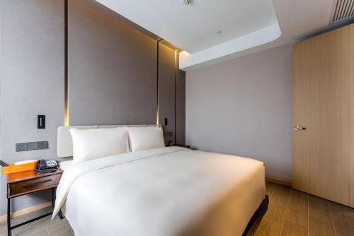 a large white bed in a room with a door at Atour Hotel Shengzhou in Shengzhou