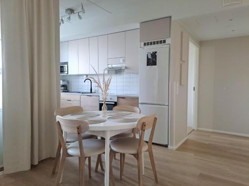 - une cuisine blanche avec une table et des chaises blanches dans l'établissement Upea saunallinen kaksio Sibeliustalon vieressä, à Lahti