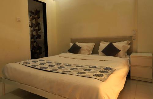 a bedroom with a large bed with white sheets and pillows at The Retreat by City Homes Aashiyaanaa in Jambhulpāda