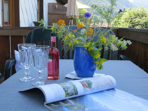 a table with a book and wine glasses and a bottle at Pension Marianne - Chiemgau Karte in Inzell