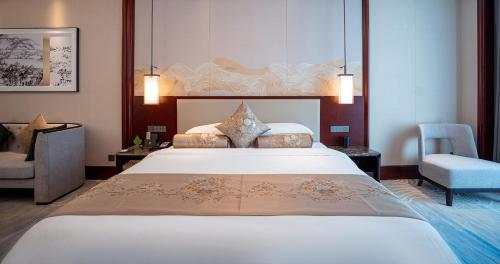 a hotel room with a large bed and a chair at Yancheng Shuicheng Hotel in Yancheng