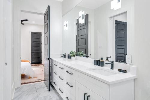 Baño blanco con lavabo y espejo en Modern Mid-city Maison en Nueva Orleans