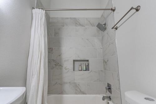 baño con ducha con cortina blanca en Revived Nola Home Near Everything!, en Nueva Orleans