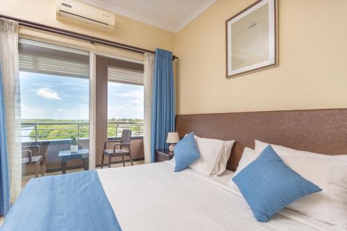 ein Schlafzimmer mit einem Bett mit blauen Kissen und einem Balkon in der Unterkunft The Waterfront in Negombo