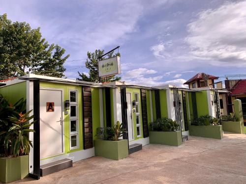 J & J Homestay في كورون: صف من المباني الخضراء والبيضاء مع النباتات