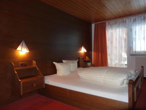 a bedroom with a large white bed with a window at Köflerhof Appartements in Sankt Leonhard im Pitztal