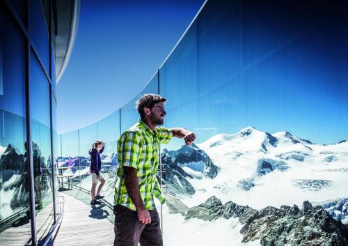 a man standing in front of a building with a mountain mural at Köflerhof Appartements in Sankt Leonhard im Pitztal