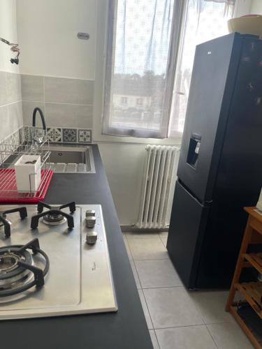 kuchnia z kuchenką i czarną lodówką w obiekcie Appartement spacieux w mieście Nogent-le-Rotrou