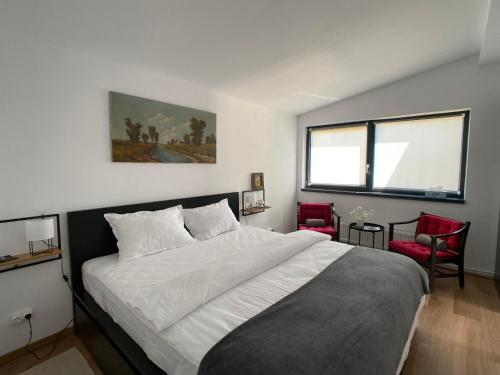 1 dormitorio con 1 cama grande y 2 sillas rojas en Nest in Gărâna - Cardinal House en Garana