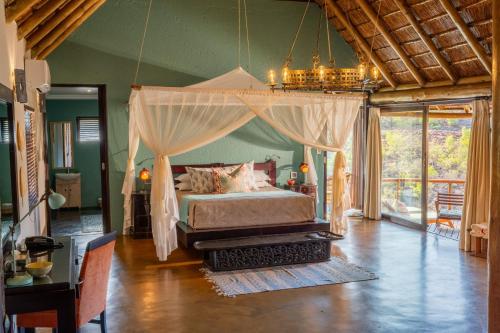 - une chambre avec un lit à baldaquin dans l'établissement Sediba Luxury Safari Lodge, à Réserve animalière Welgevonden