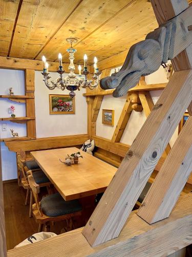 a dining room with a wooden table and a chandelier at Andi's Skihotel in Obertauern