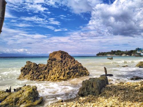 a beach with some rocks in the water at Molinillo Vacation Cabin in Ginatilan