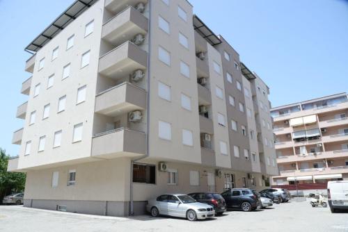 ein hohes Gebäude mit Autos auf einem Parkplatz in der Unterkunft Apartment Chloee in Gevgelija