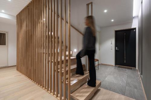 Una donna che scende una scala di legno in una casa di Enter Tromsø Luxury Villa a Tromsø