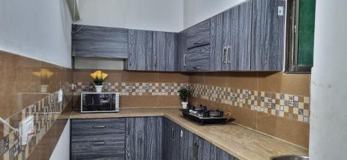 a kitchen with wooden cabinets and a microwave at Eniter Two Bedrooms Luxry Apartment in Karachi