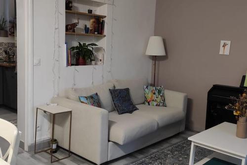 un sofá blanco con almohadas en la sala de estar en Calme à 3 min de la Gare de Melun en Melun