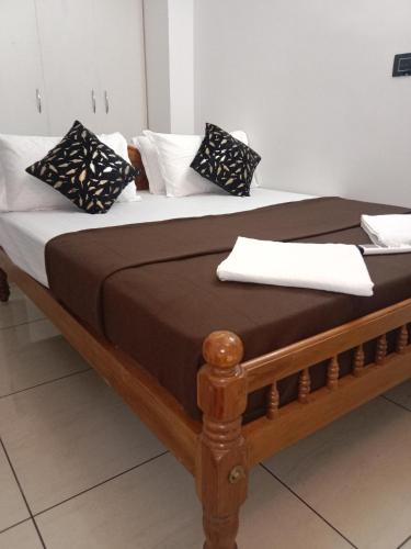 een bed met een houten frame met kussens erop bij Kochi Bella Villa in Cochin